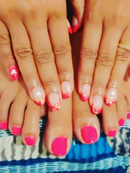I love creating a complete look with matching hands and feet. Here, I've paired a vibrant, solid hot pink pedicure with a detailed French manicure that has glitter and small heart accents for a fun, coordinated style.