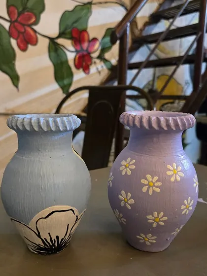The beautiful results of a fun day. These hand-painted vases, one with a delicate floral design and the other with daisies, show how a simple clay pot can become a unique piece of art.