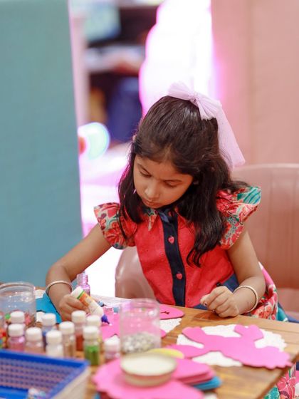 A young guest concentrates on a unicorn-themed craft activity. We provide all the supplies for creative fun, including glitter and colorful paper.