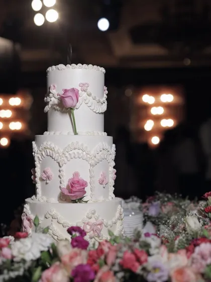 A stunning three-tiered wedding cake featuring classic Lambeth piping and adorned with single, elegant pink roses. This cake was the star of a beautiful reception.