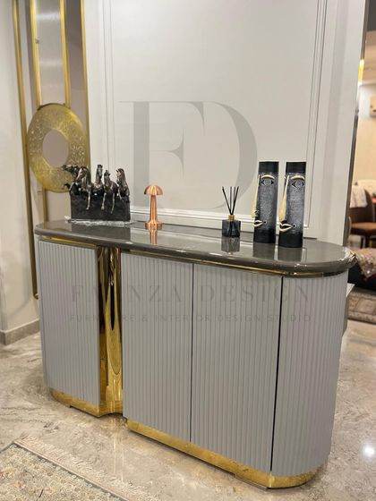 A full view of the grey and gold console, showing its elegant curves and how it can be styled with decorative objects to create a welcoming and personal entryway.