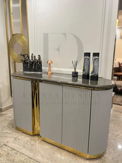 A custom console table with a unique, split-level design. The piece features a grey fluted body, a marble top, and a central accent in a high-shine gold finish, making it a sculptural and eye-catching item.