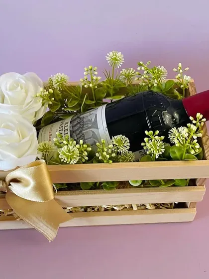 A simple and elegant wine hamper. A bottle of wine is beautifully presented in a wooden crate with white roses. This is available for Bangalore delivery only.