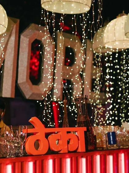 The 'Theka' is where the magic happens. This bar setup featured a fun, desi-inspired sign, set against a backdrop of cascading fairy lights and modern marquee letters for a playful yet chic cocktail experience.