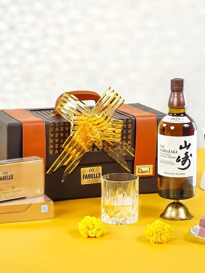 An elegant Diwali gift hamper featuring a bottle of Yamazaki whisky and a Fabelle chocolate fondue set. The minimalist styling on a bright yellow background exudes sophistication.