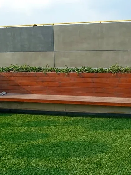 A custom-built wooden bench with integrated planters on either side. This functional piece provides seating while seamlessly incorporating greenery into the rooftop design.
