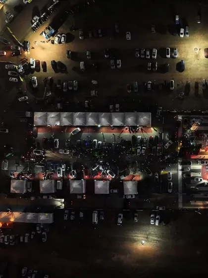 A top-down view of the illuminated expo area at night. This is the central hub of the festival, where brands, fans, and racers connect.