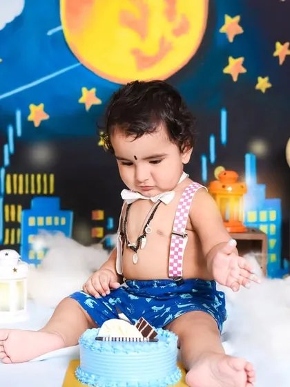 Getting ready to dive into his first birthday cake. This little superhero is contemplating his next move in front of a cityscape backdrop designed for his special day.