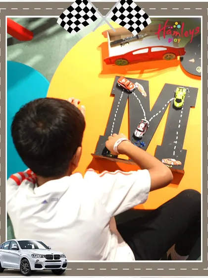 Another creative station at our Mini Racers event, where a child uses toy cars to trace the letter 'M'. I love incorporating educational elements into our play activities.