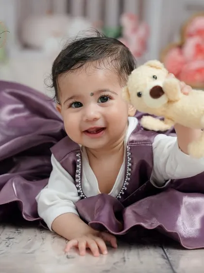 A happy smile and a playful pose with her teddy bear make this a heartwarming and memorable shot from her milestone session.