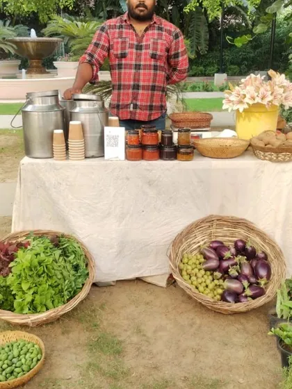 A farmer at his stall with fresh produce and homemade drinks, ready to serve customers.