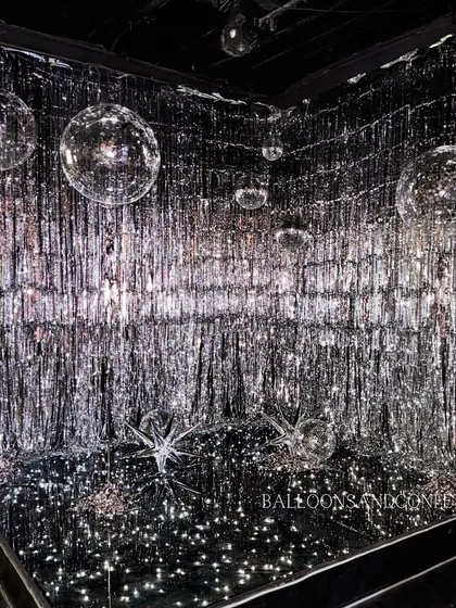 The final result of our glitter-filled photo booth. A silver fringe curtain, mirrored floor, and floating disco balls create a truly immersive and dazzling experience.