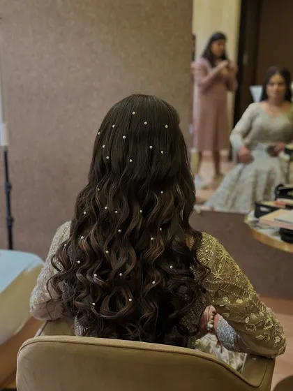 This shot shows the client's reflection, giving a glimpse of the full look with the pearl-adorned hair.
