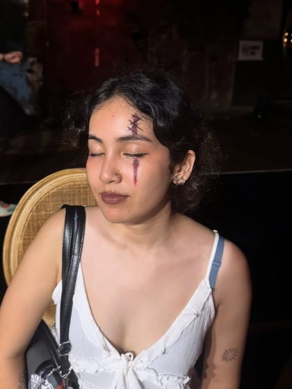 A close-up of the stitched wound and bloody tear effect with eyes closed, highlighting the texture and detail.