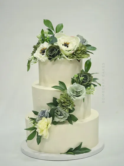A simple yet stunning three-tier buttercream cake with a cascade of green and white sugar flowers.