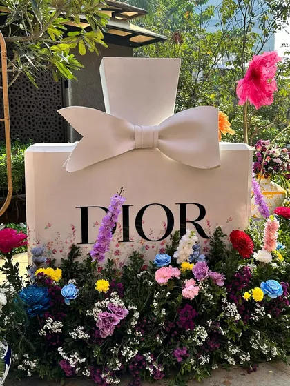 Pre-wedding events should be full of personality and chic fun. This Dior-inspired Haldi setup features a larger-than-life perfume bottle installation surrounded by a garden of vibrant, multi-colored flowers, creating a fashionable and playful atmosphere for celebration.