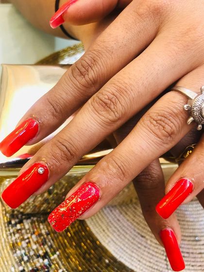 A close-up of the glitter and stone details on one of the red accent nails.