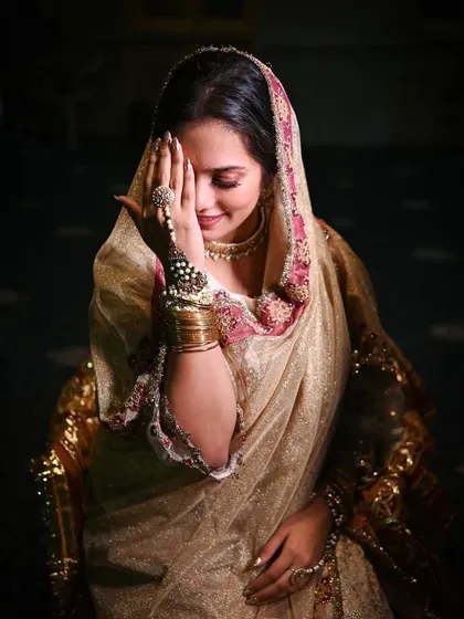 A shy, happy smile from the bride during her wedding reception. This candid portrait captures a moment of bashful joy, highlighting her stunning traditional attire.