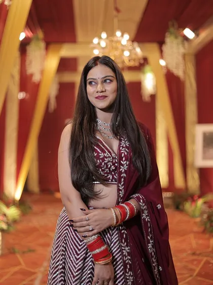 A close-up of a client in the maroon chevron lehenga, showing her beautiful smile and the intricate details of the blouse.