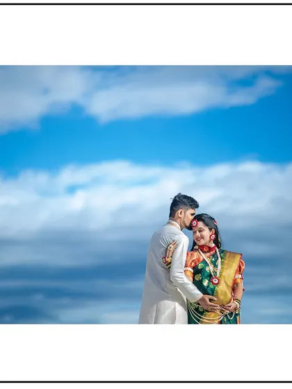 A stunning maternity portrait celebrating Maharashtrian heritage. The vibrant Nauvari saree and traditional jewelry look incredible against the dramatic sky, creating a timeless memory for the expecting couple.