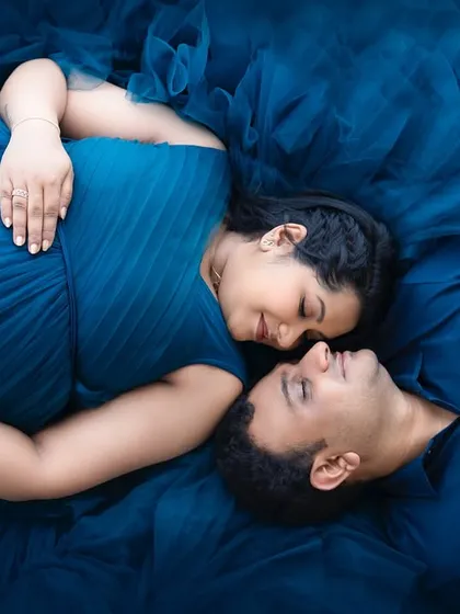An artistic overhead shot from a maternity session, with the couple surrounded by a sea of deep blue fabric. This creative approach to pregnancy photography highlights the beauty and intimacy of this special time.