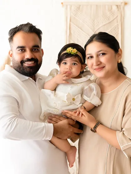 A happy family portrait featuring a mother, father, and their baby, captured in a bright, naturally lit setting with a boho-chic theme. I aim to capture genuine connection and joy in my family sessions.