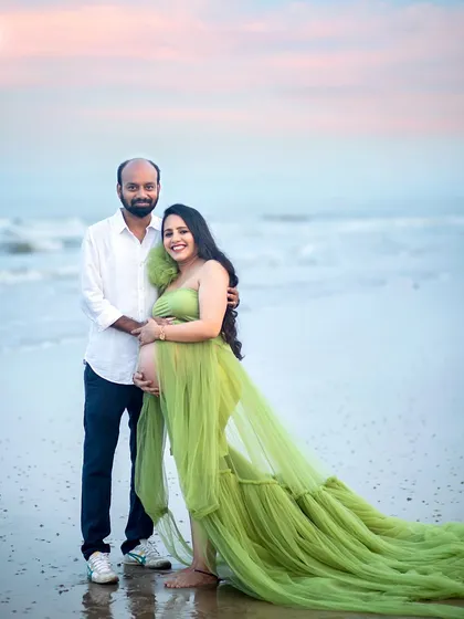 A full-length portrait showcasing the couple and the gorgeous flow of the maternity gown against the ocean backdrop.