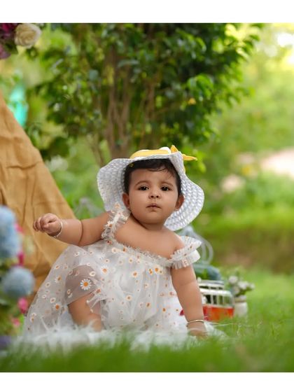 An adorable outdoor portrait of a baby girl in a sun hat, enjoying a beautiful day. Outdoor sessions are a great option for older, more active babies.