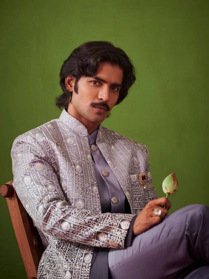 A close-up of the model holding a lotus bud, a symbol of purity and beauty that reflects the essence of the Nazaakat collection. The focus is on the intricate details of the outfit.