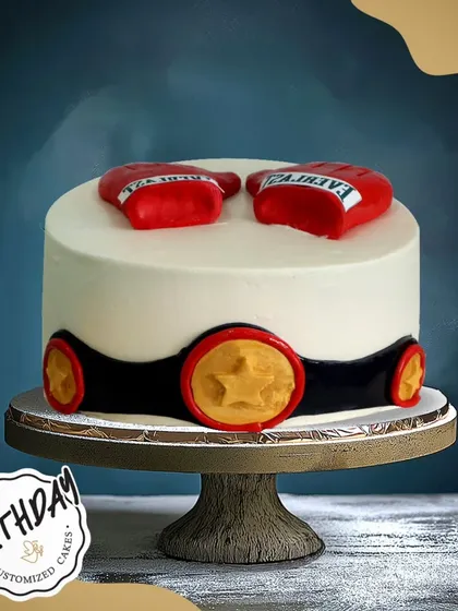 A knockout of a cake for a boxing fan. This design features red boxing gloves and a champion's belt, ready for the main event.
