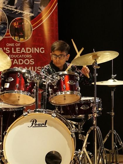 A young drummer focuses intently during his performance at the FSM Thane Recital. Our drum lessons cover everything from basic rhythms to complex solos, preparing students for powerful stage performances.