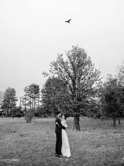 A lone bird flies overhead as they embrace in the vast Kashmiri landscape. A wide, atmospheric shot that feels both lonely and incredibly romantic, like they are the only two people in the world.