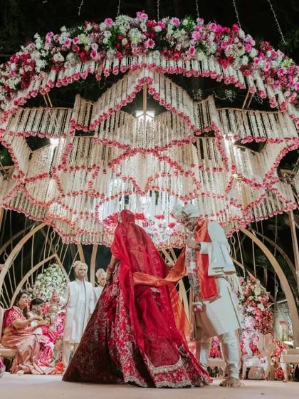 The Varmala ceremony under a spectacular Lotus-themed mandap. The ceiling is a breathtaking creation of hanging white and pink florals, forming the shape of a blooming lotus.