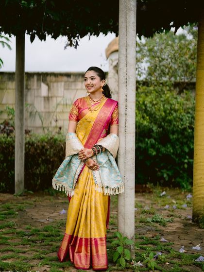 A full view of a classic Maharashtrian bridal look. The simple ponytail hairstyle allows the beautiful saree and traditional jewelry to really shine.