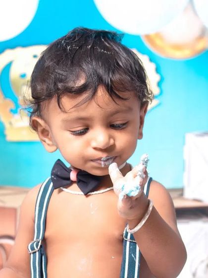 A little prince celebrating his first birthday with a royal blue cake smash. The setup includes a crown, balloons, and a delicious-looking cake ready to be smashed.