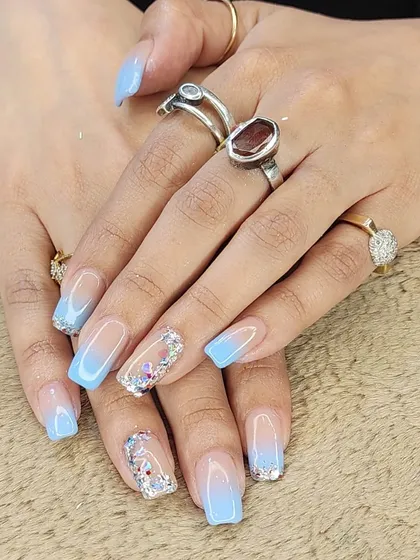 A beautiful "glass" nail effect. This set features a light blue ombre with encapsulated glitter and butterfly sequins, creating a multi-dimensional and sparkling look.
