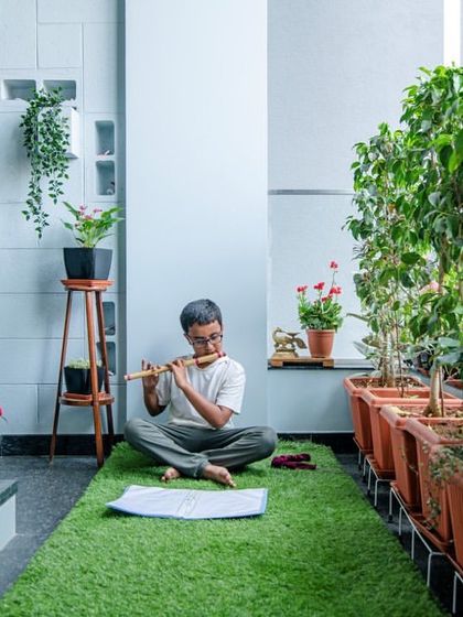 Close to divinity. A quiet moment of peace, playing the flute in a green-filled indoor courtyard, showcasing how we design spaces for tranquility and personal reflection.