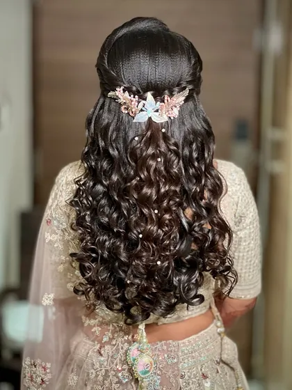 A detailed view of the half-up, half-down curly hairstyle, adorned with a delicate hair accessory.