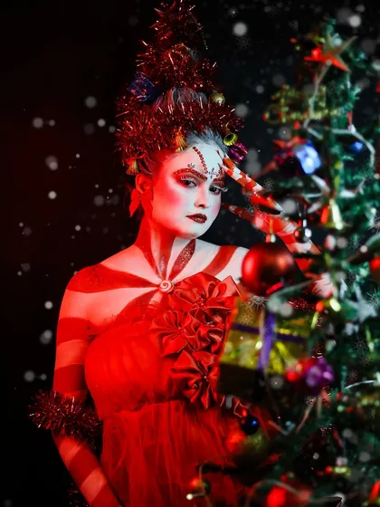 A festive Christmas-themed look, transforming the model into a human candy cane next to a Christmas tree. This showcases skills in body painting and thematic holiday makeup.