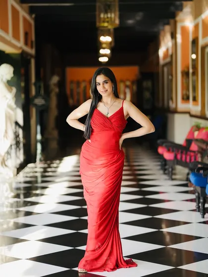 A full-length shot in the red gown, standing in a beautiful corridor. The setting perfectly complements the outfit.