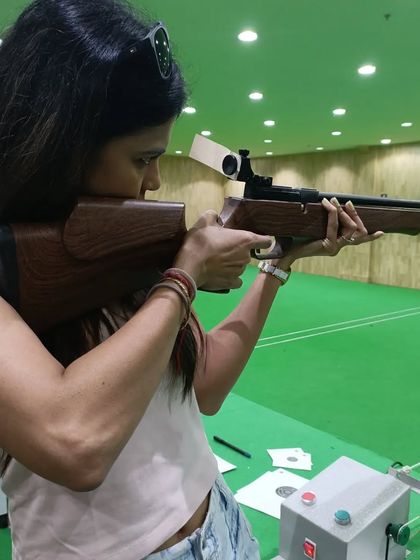 A different angle of Ms. Murgunde's session, showing her form as she aims the air rifle. Each shot is a lesson in patience and precision.