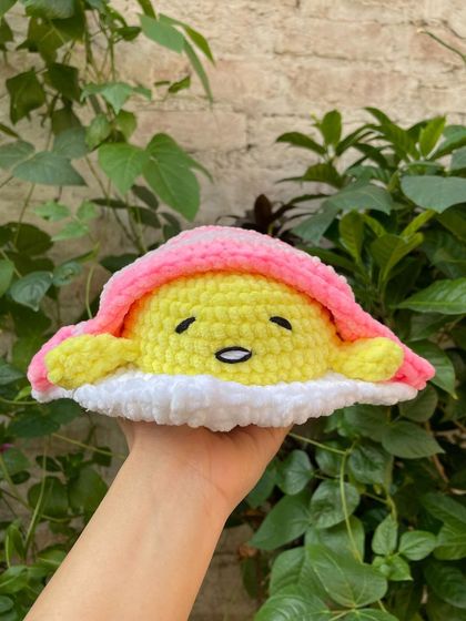 This is my crochet version of Gudetama, the lazy egg, made with soft plush yarn. He's resting on his egg white blanket, looking perfectly unmotivated.