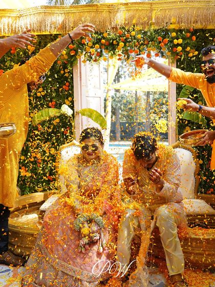 A candid shot of the couple being showered with flower petals during their Haldi. It's a moment of pure, unadulterated joy.