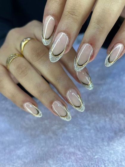 An elegant French manicure with a twist, featuring a glittery gold outline on the tips.