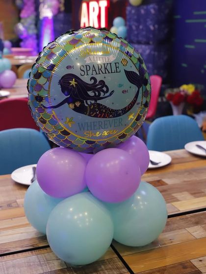 A themed table centerpiece for a mermaid party. Even the tables get a touch of magic with these custom balloon arrangements topped with mermaid foil balloons.