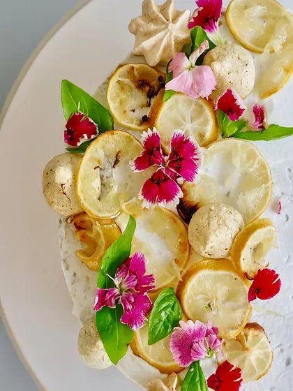 A close-up of the zesty, herby, and unique Lemon Basil cake. I top it with candied lemons, fresh basil leaves, and edible flowers for a dessert that is as beautiful as it is adventurous.