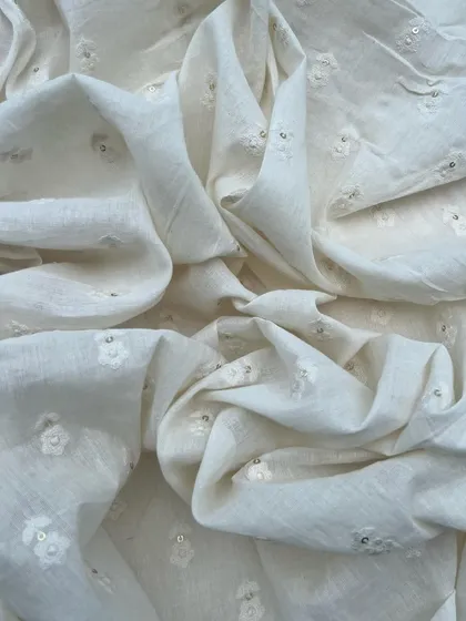 A close-up of our white embroidered cotton, showing the delicate floral butis and sequin accents that make this fabric so special.