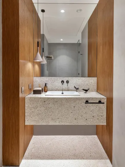 The bathroom for the reader's retreat features a cast in-situ terrazzo counter and flooring. This is paired with microconcrete walls and wood accents, creating a space that is both tactile and highly functional.