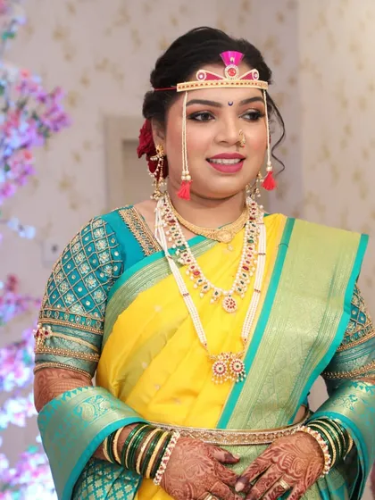 A full view of the bride in her traditional attire, showcasing the beautiful color combination of her saree and blouse.