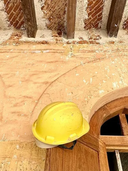 A yellow hard hat rests on a door frame, a simple object that symbolizes the ongoing work and the presence of the craftsmen who are healing the building.
